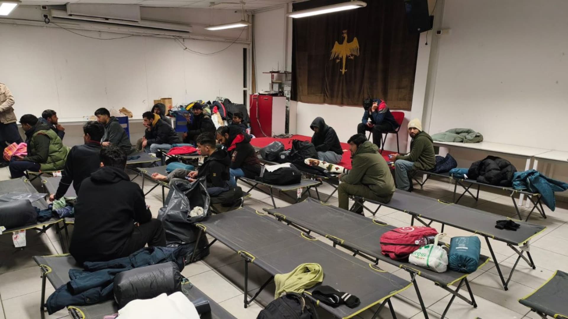 I migranti nel dormitorio improvvisato in attesa del trasferimento