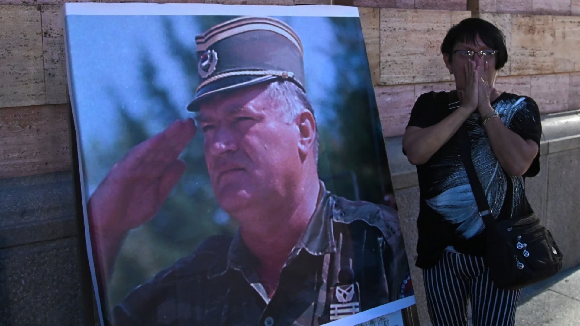 Una donna piange accanto alla foto di Mladic